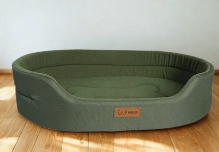 Grünes ovales Hundebett mit erhöhtem Rand aus Stoff, gepolsterter Liegefläche und atmungsaktivem Material – bequemes Komfortbett für kleine und mittelgroße Hunde.
